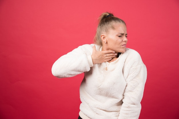 A young woman holding throat and suffering from pain