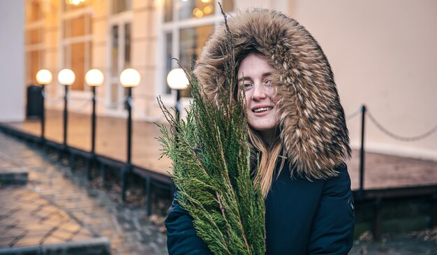 A young woman holding thuja branches blurred background with bokeh lights