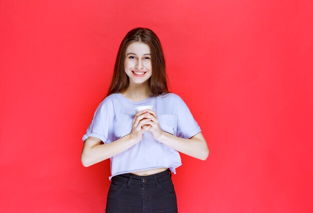 young woman holding a white disposable water cup.