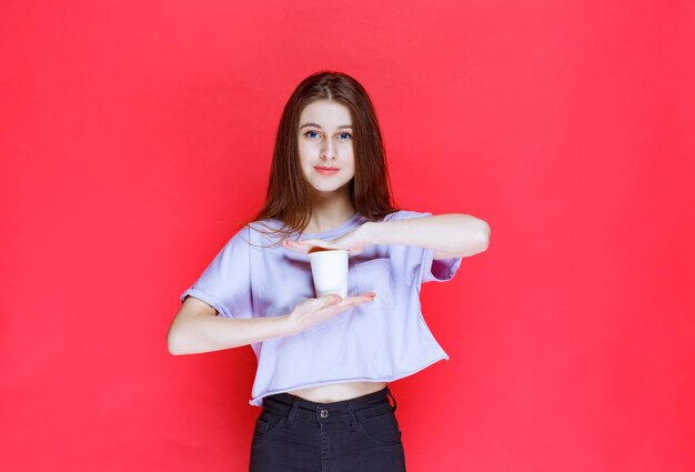 young woman holding a white disposable water cup.