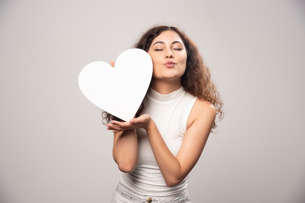 Young woman holding white handmade paper heart. High quality photo