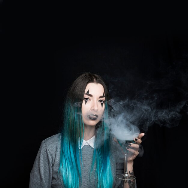 Young woman holding wineglass with smoky drink