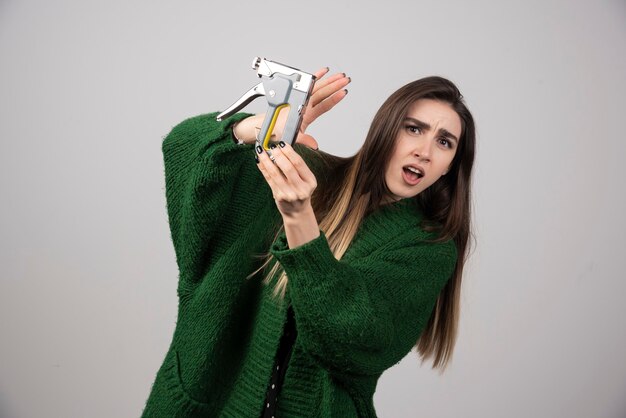 A young woman holding a working tool on a gray background.