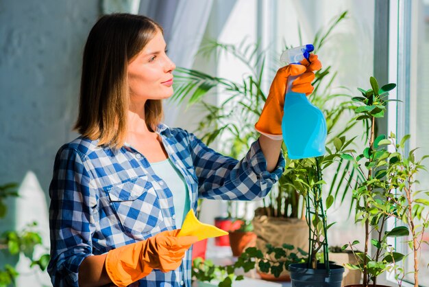 Young woman holding yellow napkin spraying on window glass