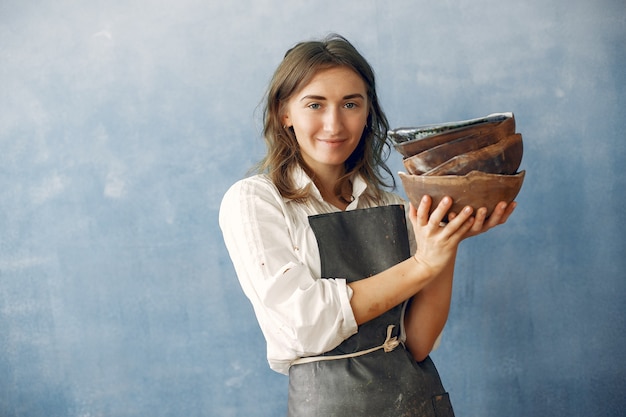 Free photo a young woman holds a ceramics dish in her hands