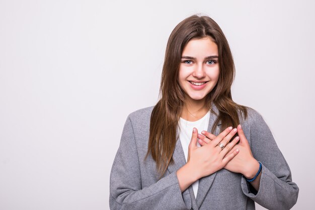 A young woman holds her hands on his chest with his eyes closed on a gray background.