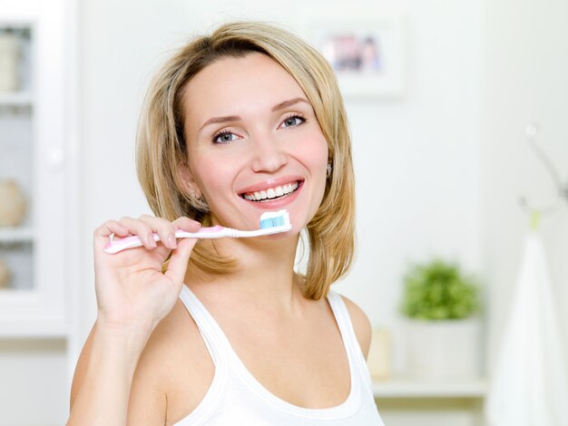 若い女性は、歯磨き粉で歯ブラシを保持します