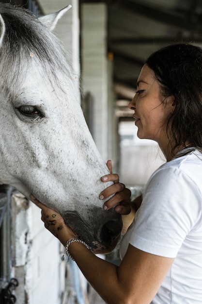 若い女性と馬、感情、ケア、愛情、優しさ、女性は馬を抱きしめてキスします。彼女の馬を抱き締める幸せな若い女性のクローズアップ。