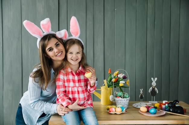 Young woman hugging daughter in bunny ears