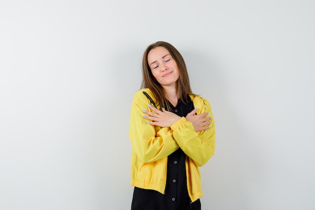 Free photo young woman hugging herself and looking happy