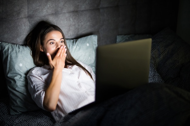 Бесплатное фото Молодая женщина в постели с ноутбуком в ночи
