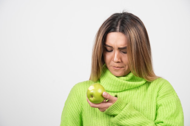 Молодая женщина в зеленой футболке держит яблоко