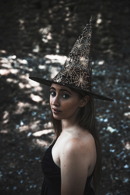 무료 사진 카메라를보고 마법사 모자에있는 젊은 여자