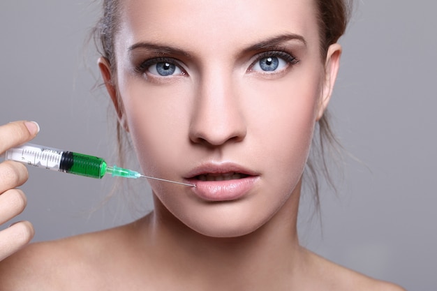 Free photo young woman injecting for a beauty treatment