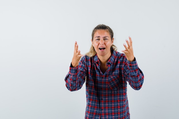 Young woman inviting to come in checked shirt and looking exhausted