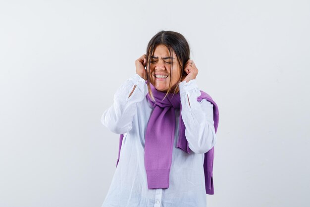 The young woman is covering her ears with hands on white background