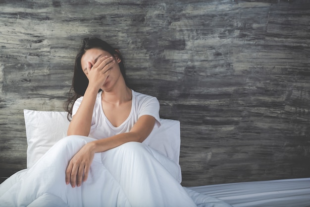 Young woman is depressed on a white bed