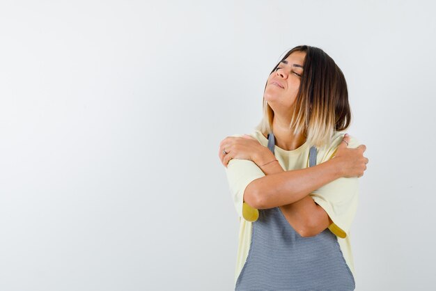 The young woman is dreaming with crossing arms on white background