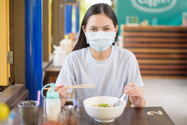 Premium Photo | A young woman is eating thai street food , wearing face  mask, new normal eating concept