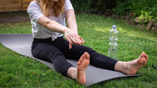 A young woman is engaged in fitness in nature on a rug