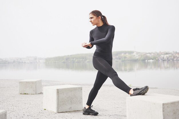 A young woman is engaged in sports on the shore of a lake in the park