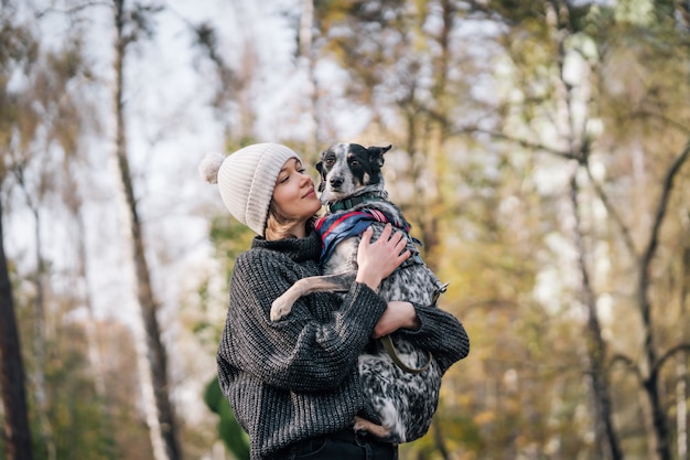 若い女性は彼女の腕の中で犬を保持しています。