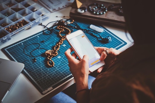 Free photo young woman is making photo of her beautiful beads bracelets via smartphone.