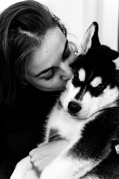 A young woman is playing with a husky puppy