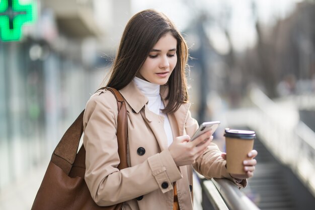 Молодая женщина читает новости на свой телефон за пределами
