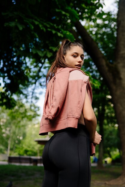 Young woman is resting after jogging in the park.