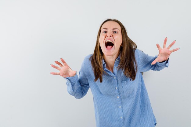 The young woman is scaring by opening wide her hands on white background