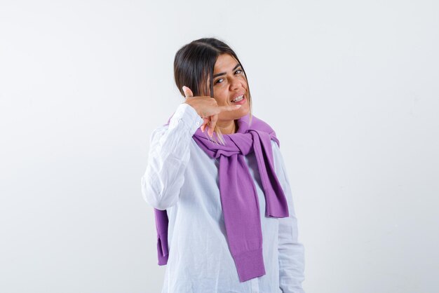 The young woman is showing mobile phone gesture with hand on white background