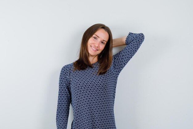 The young woman is smiling by holding her hand behind head  on white background