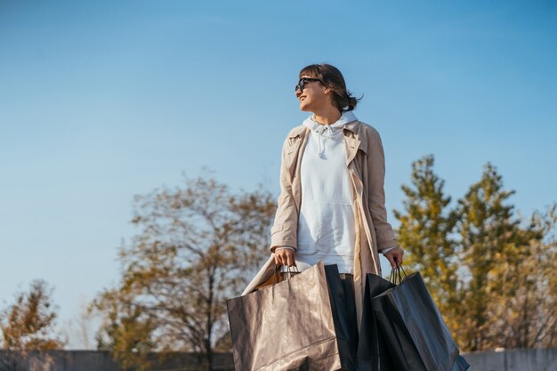 A young woman is standing in a car with bags in her hands