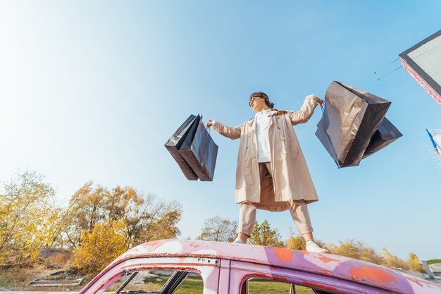 A young woman is standing in a car with bags in her hands