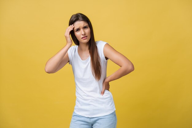 젊은 여성이 노란색 배경 스튜디오 샷에 두통을 앓고 있다