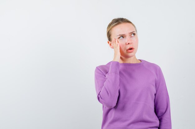 The young woman is thinking by holding her forefinger on temple on white background