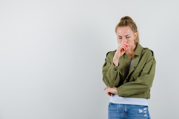 The young woman is thinking by holding her hand on nose on white background