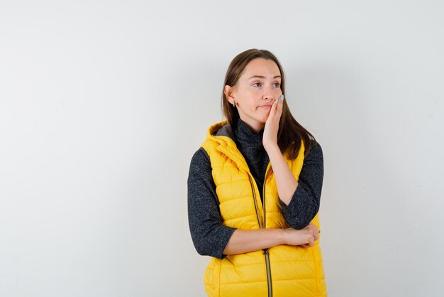 The young woman is thinking by putting her hand on cheek on white background