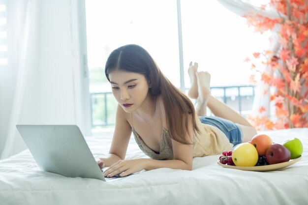 Молодая женщина смотрит фильм с ноутбуком на кровати у себя дома