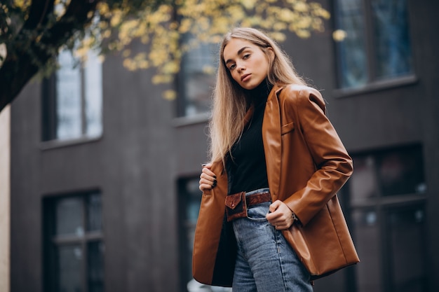 Young woman in jacket walking out in the city