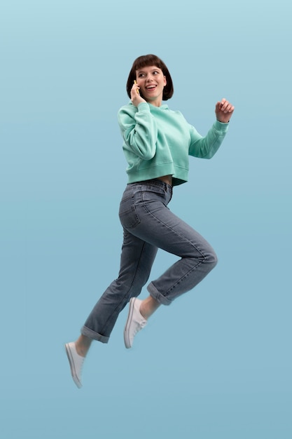 young woman jumping isolated on blue