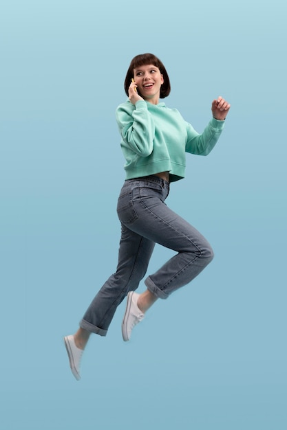 Молодая женщина прыгает изолированной на синем