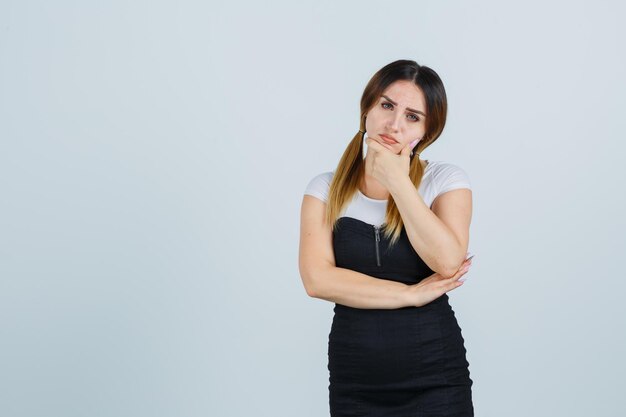 Young woman keeping hand on chin and looking pensive