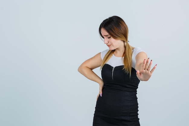 Free photo young woman keeping hand on hip while showing stop gesture