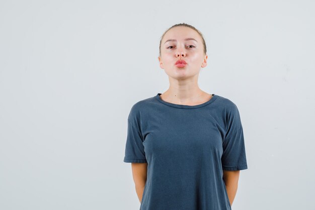 Young woman keeping lips folded in gray t-shirt and looking lovely
