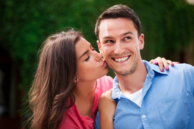 Young woman kissing her boyfriend on the cheek