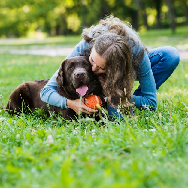 Free photo young woman kissing her dog in park