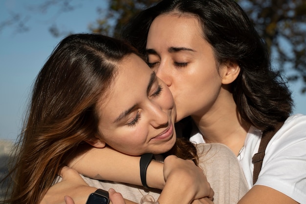 Free photo young woman kissing her girlfriend