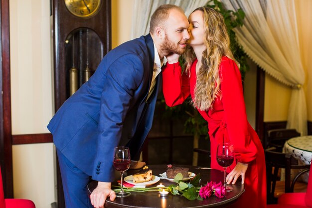 Young woman kissing man on cheek above table 